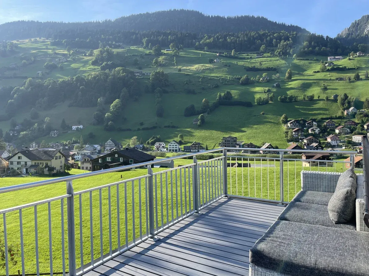 Terrasse mit Staketengeländer Classic und Edelstahlhandlauf, dahinter ein grünes Tal