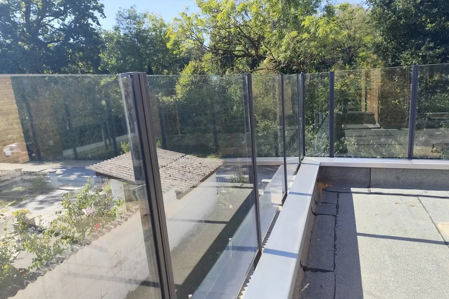 Fertiges Glasgeländer Pure auf einer Dachterrasse, Blick durch das Klarglas ins Grüne