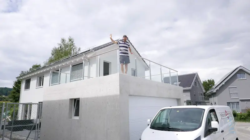 Glasgeländer Classic mit Klarglas auf einem Garagendach aus Beton, der Kunde winkt