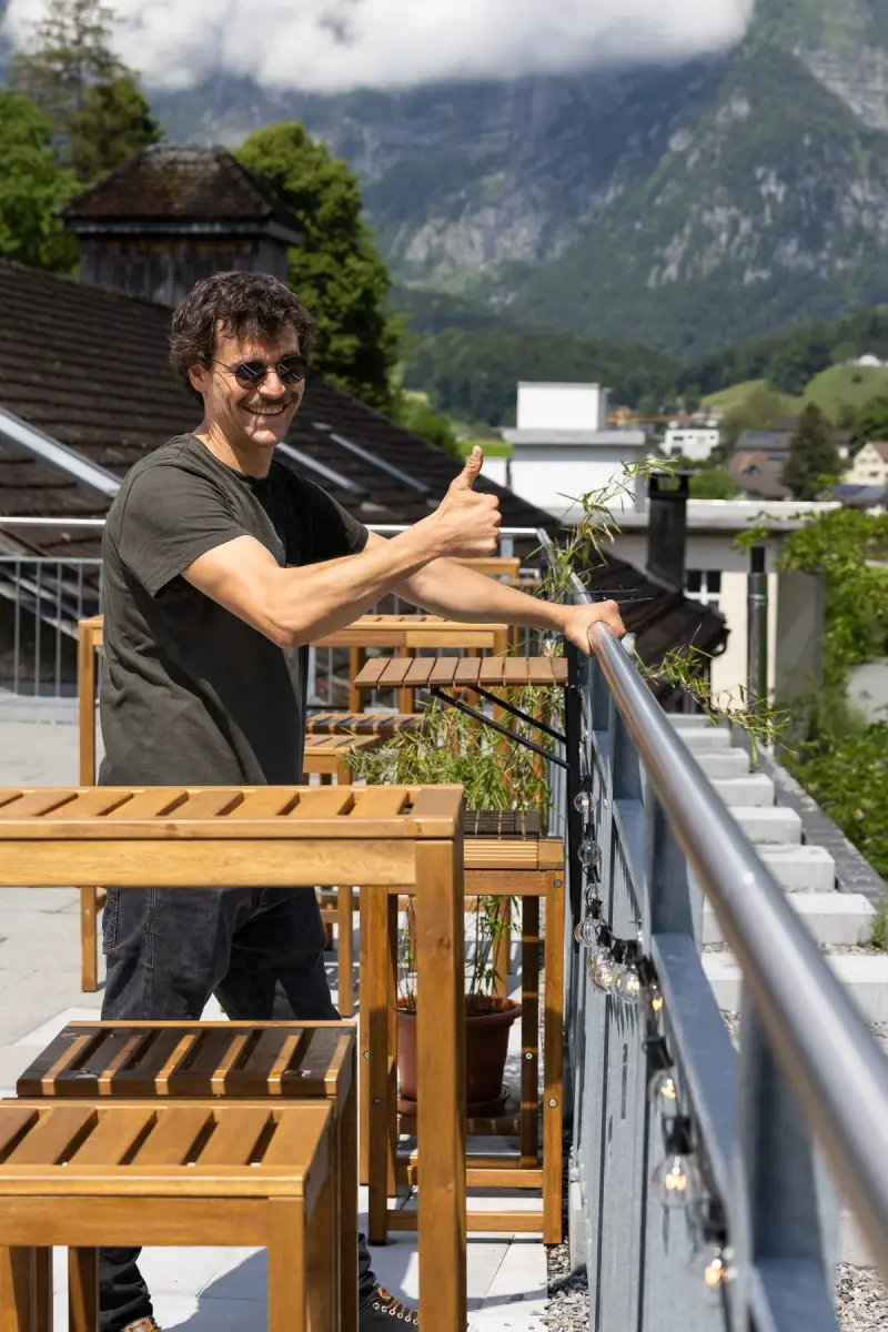 Kunde zeigt den Daumen nach oben neben seinem Staketengeländer Classic auf der Terrasse